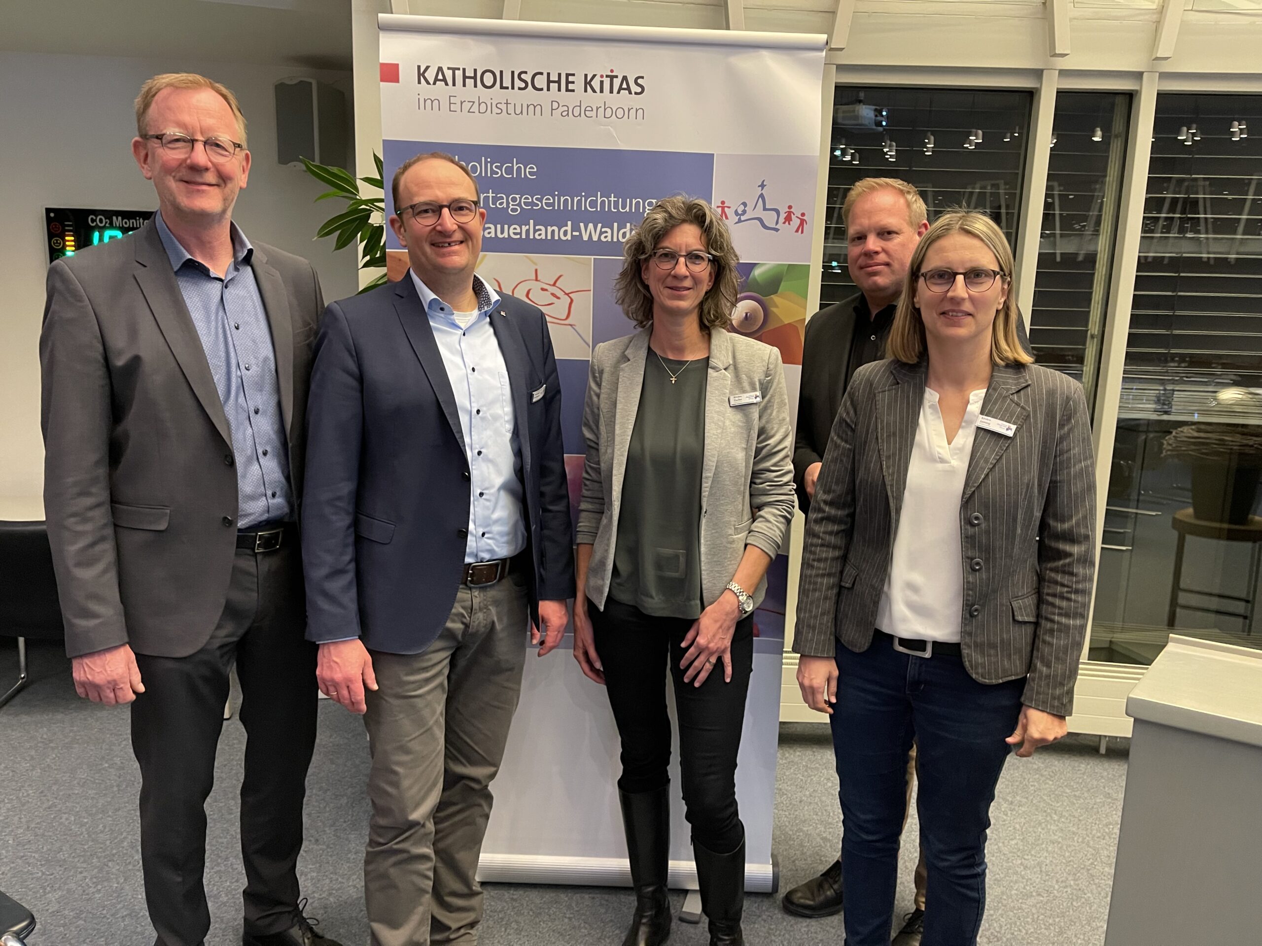 Fünf Menschen vor einem Banner mit der Aufschrift "Katholische Kitas"