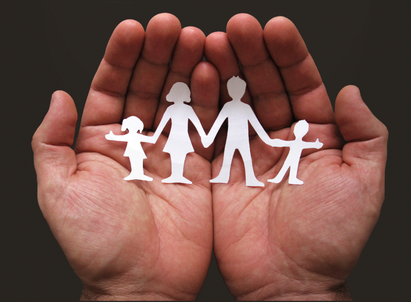 Zwei Hände halten einen Scherenschnitt, der eine Familie zeigt.