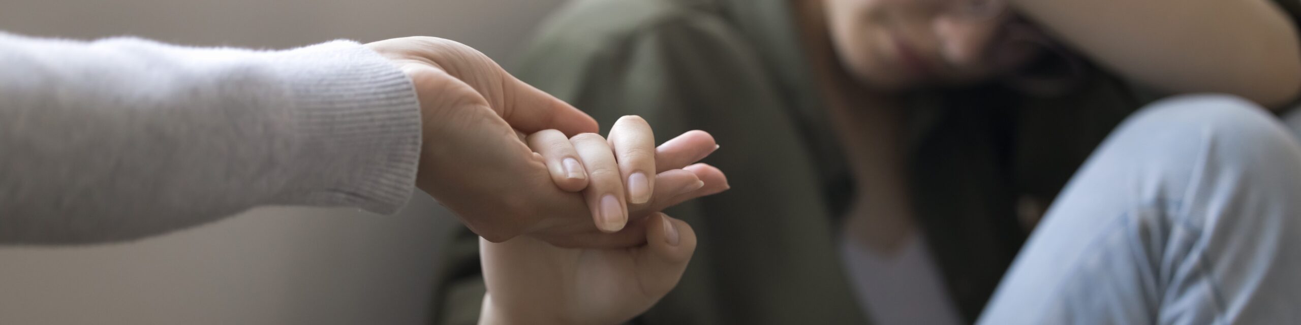 Traurige Jugendliche hält die Hand einer Erwachsenen.