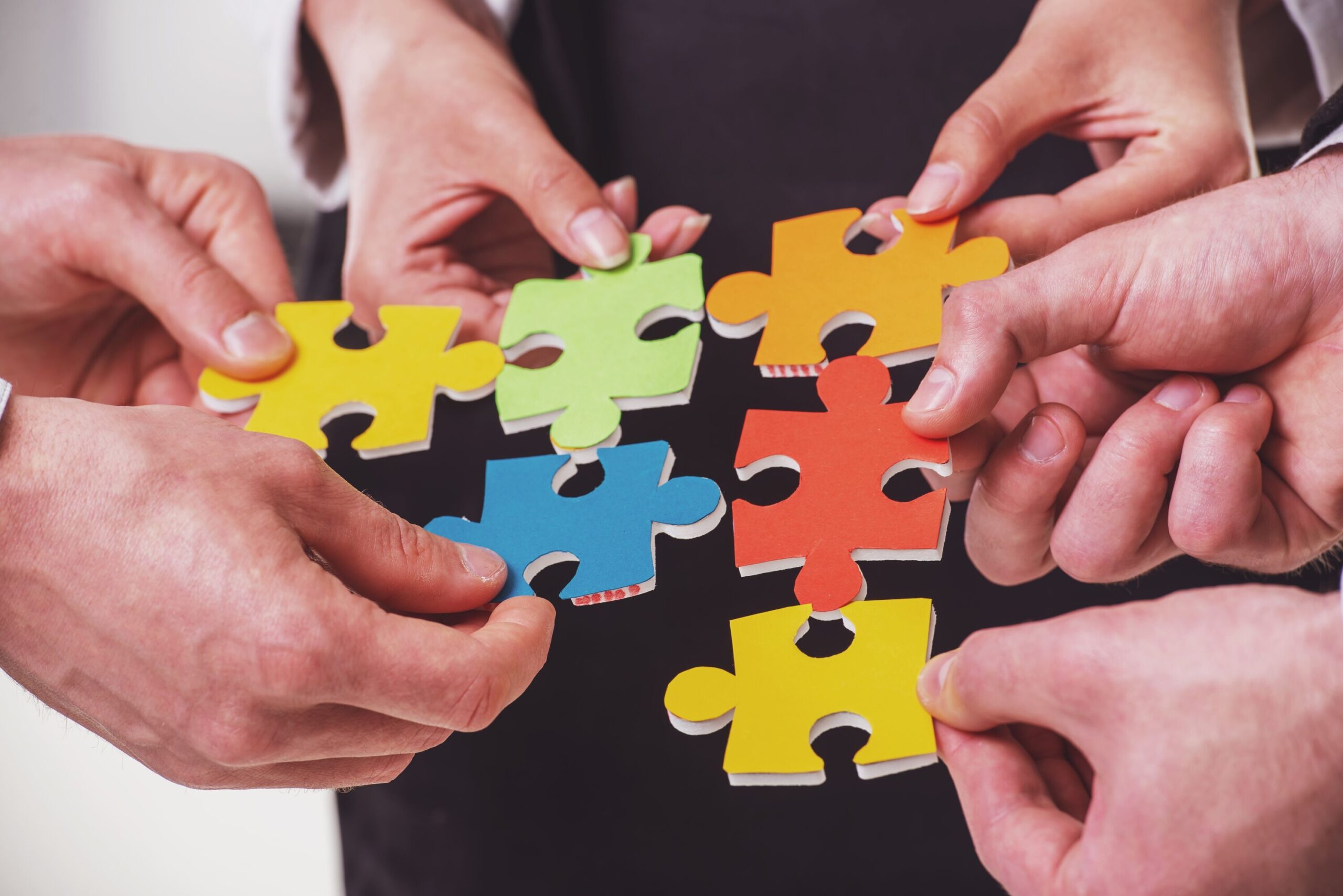 Mehrere Menschen setzen Puzzleteile zusammen