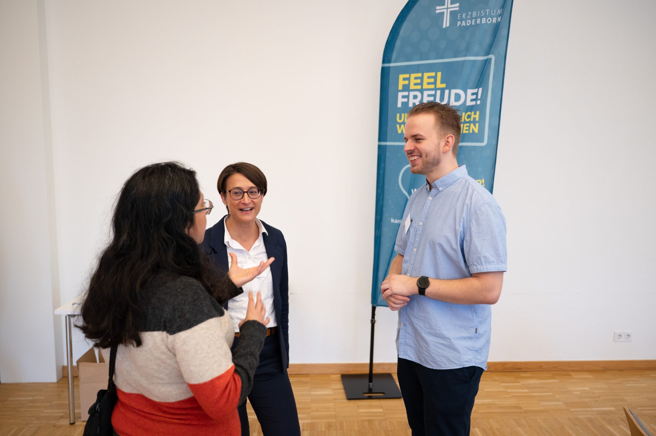 Drei Personen stehen nebeneinander und unterhalten sich.