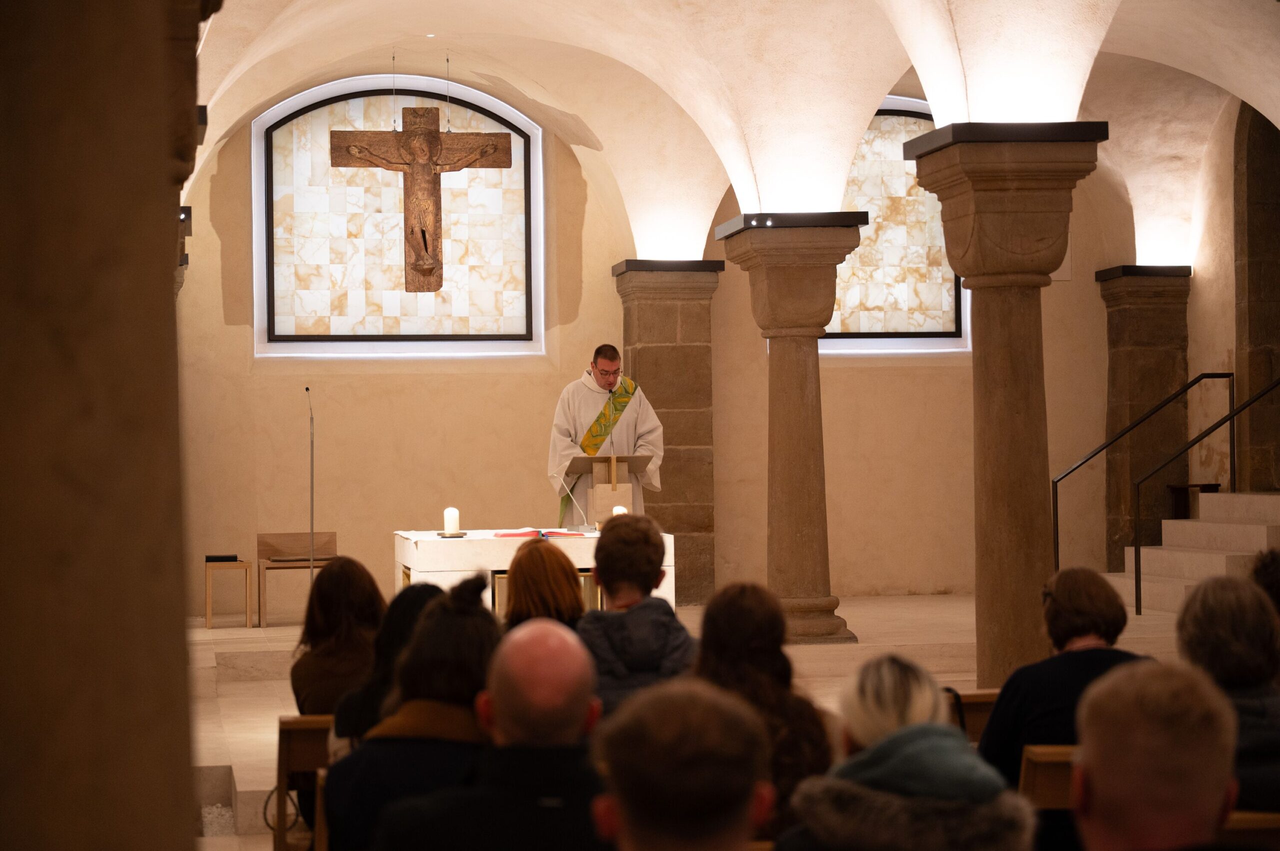 Ein Diakon steht im Gewand vorm Altar und spricht zur Menge.